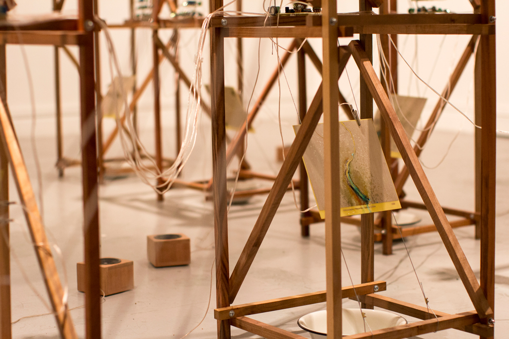 Instalación de la obra Imagen de la obra montada en el museo. Se ven las placas metálicas generadas por algoritmos, los módulos de electrónica y parlantes.